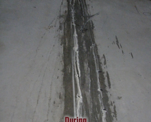 A concrete floor with a long, repaired crack filled with polyurethane grout injection sealant; a screw is embedded near the center. The word "During" at the bottom indicates the crack repair process is in progress.