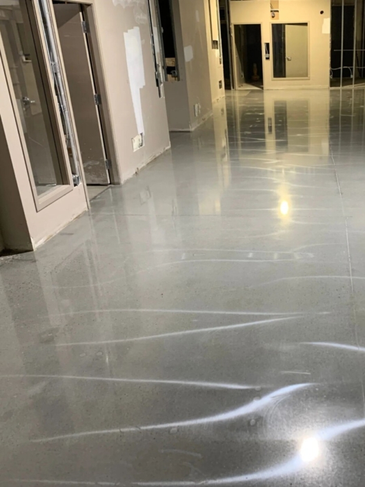 A hallway under construction with a polished concrete garage floor that is smooth and reflective.
