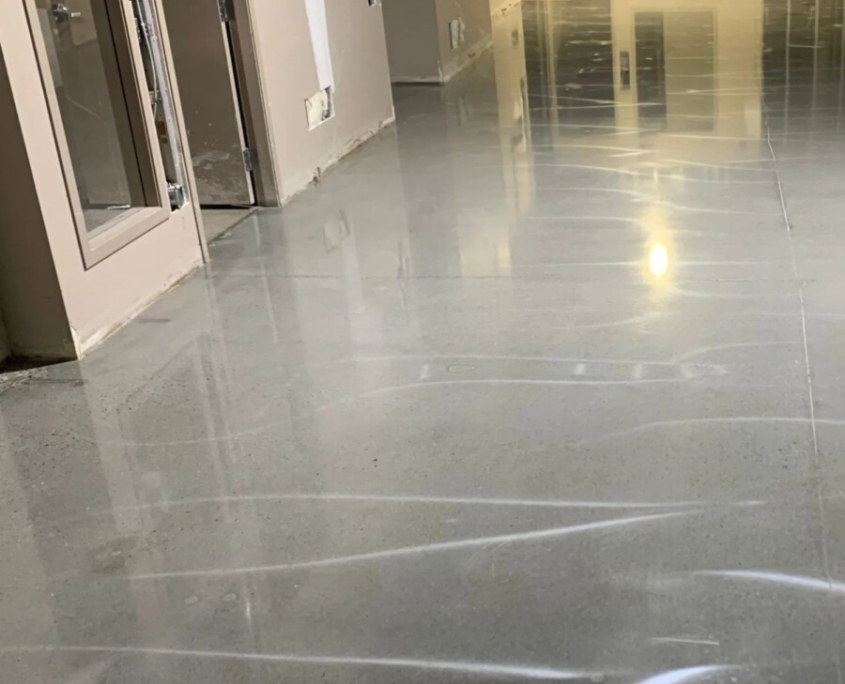 A hallway under construction with a polished concrete garage floor that is smooth and reflective.